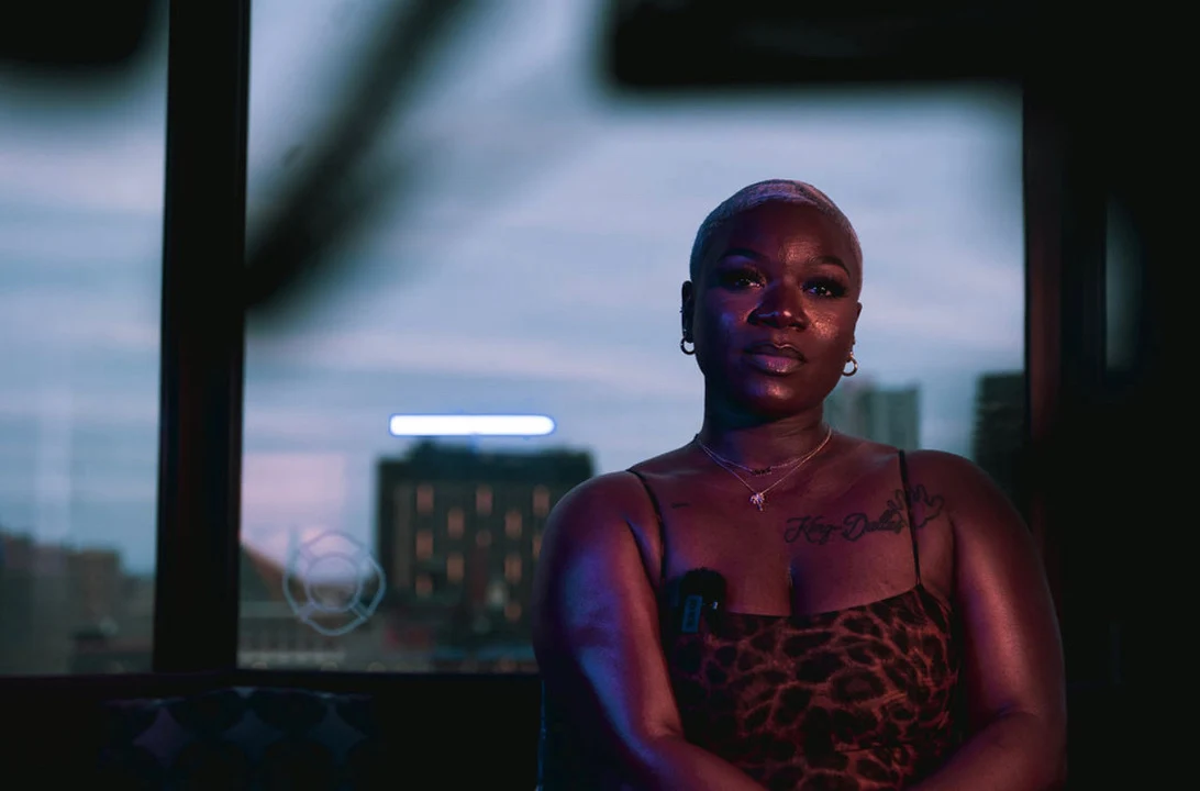 The founder by a city window at dusk, illuminated by warm red and cool blue light